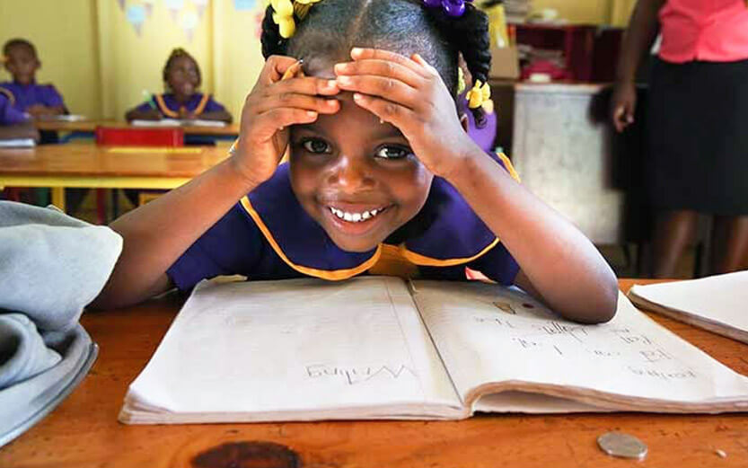 young girl at school looking up from her notebook smiling