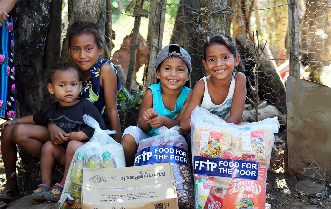 four children smiling with FFTP bags of donated food