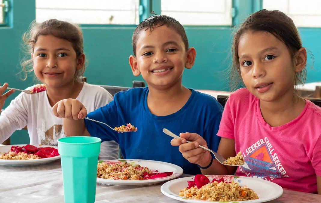 three children eating a healthy meal and smiling
