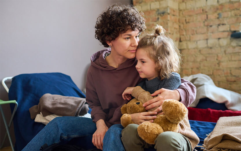 mother and young daughter with her teddy bear in a shelter