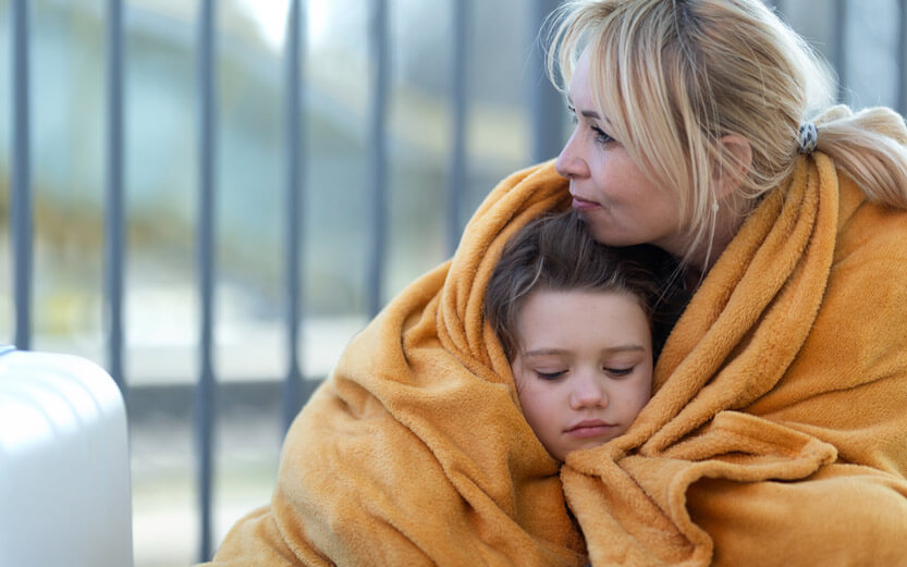 mother and son wrapped in a gold blanket outside next to a suitcase