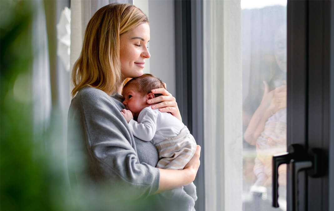 mother holding newborn with her eyes closed and smiling