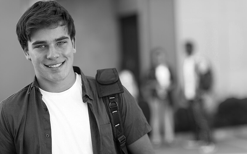 smiling teen boy carrying schoolbag