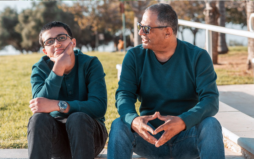 a father and teen son sitting and talking