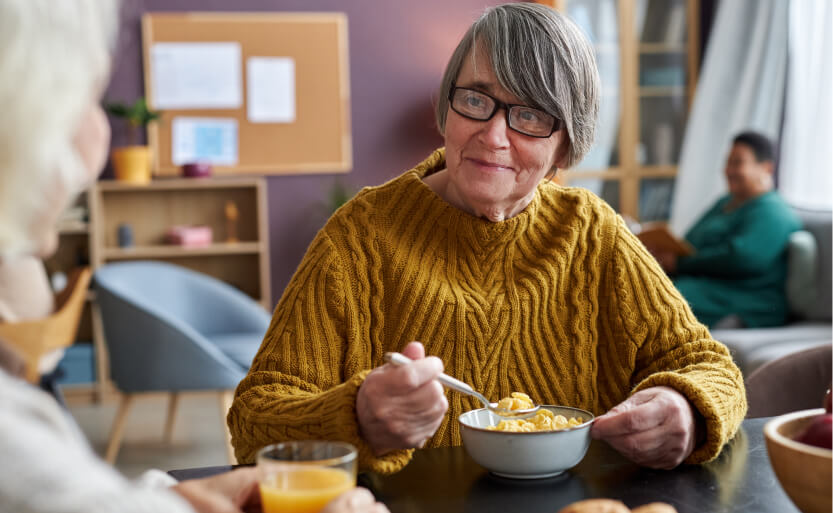 a woman sitting at a table with a bowl of cereal