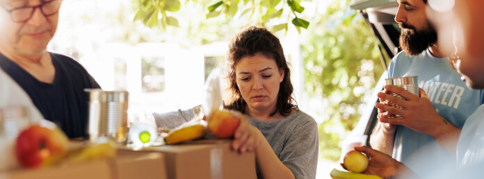 a group of people unpacking a box of fruit