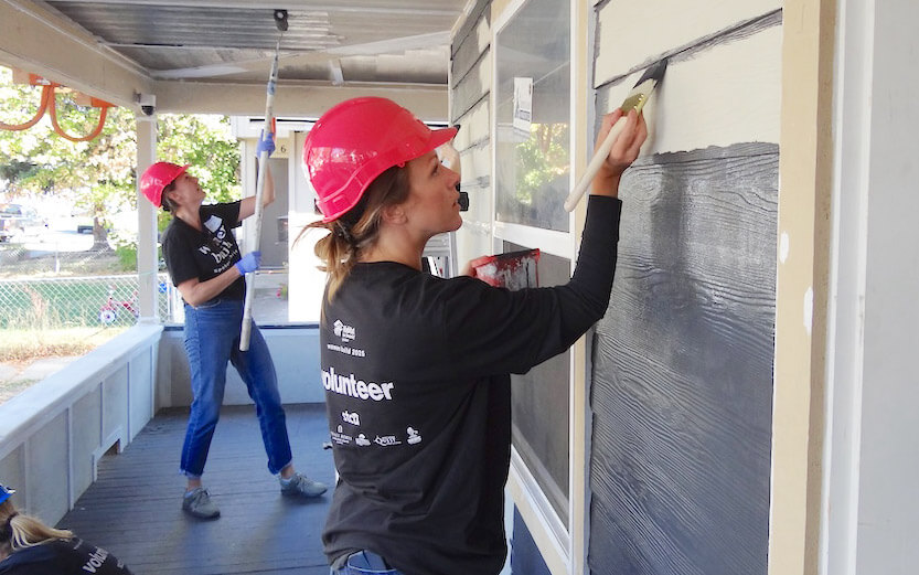 women volunteers painting the outside of a house