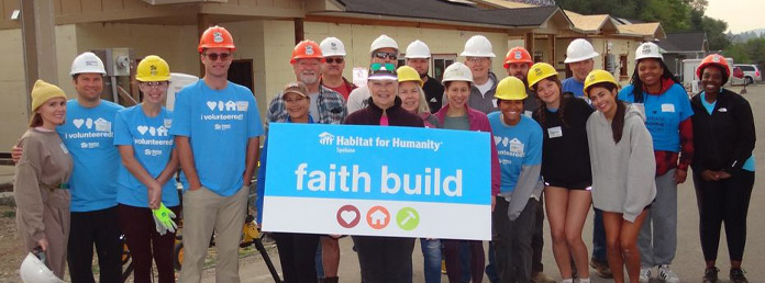 group of volunteers with a faith build sign