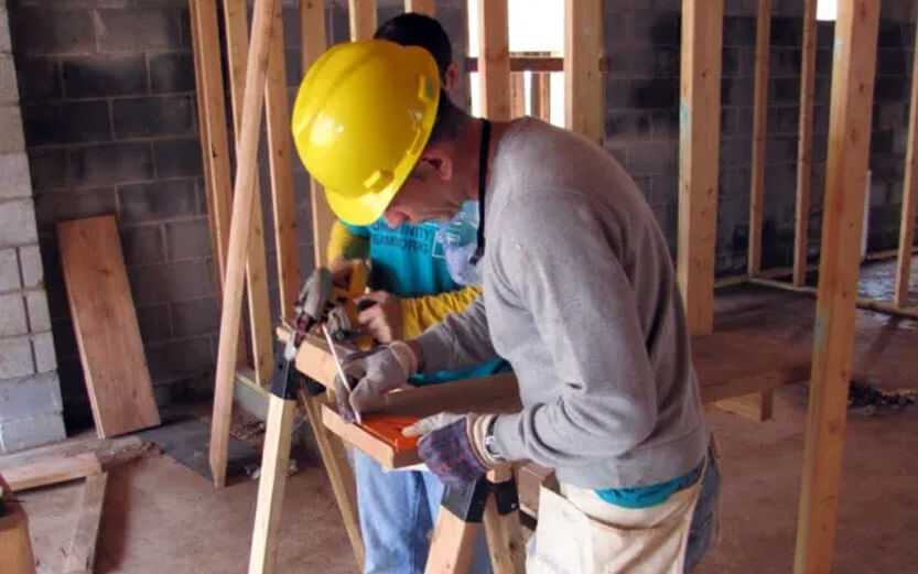 a construction worker marking wood planks