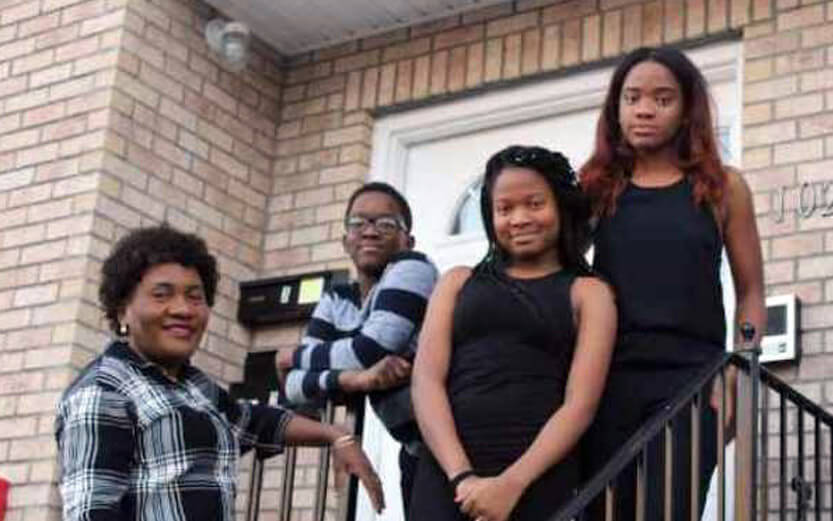 a family of four in front of their new home