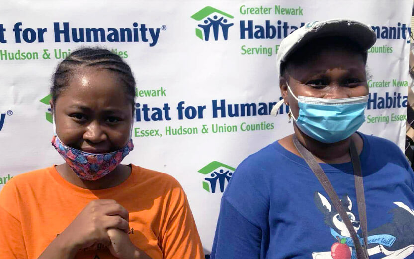 a mother and daughter standing in front of a Habitat for Humanity banner