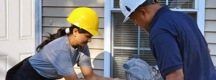 two construction workers building a house