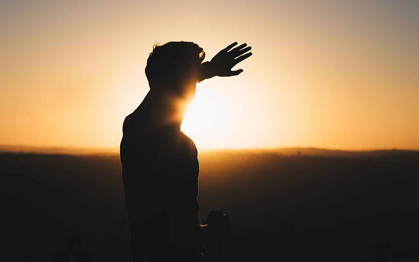 Man holding hand up to cover the sun