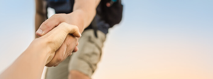 Hikers climbing mountain, helping, giving hand to friend.