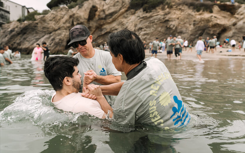 two men baptizing a man in the bay