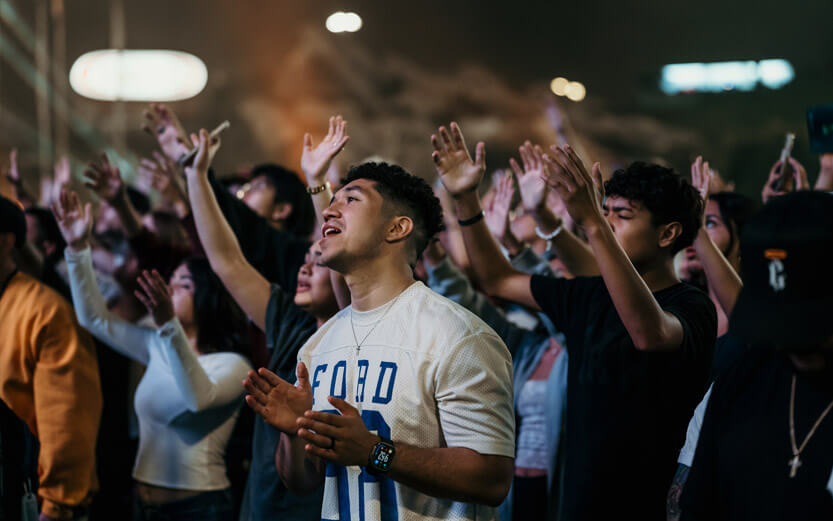 church congregation singing with focus on a young man wearing a white shirt