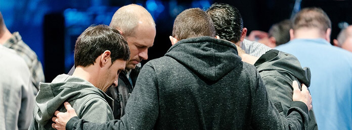 five men in a circle praying