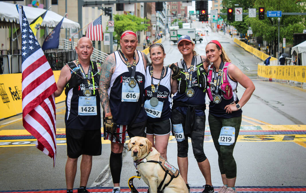 five marathon runners with dog at the end of the race