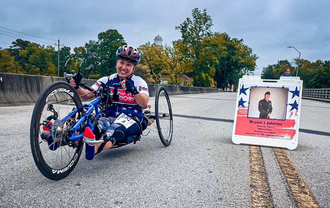 disabled woman on her bike with photo of uniformed soldier in the background