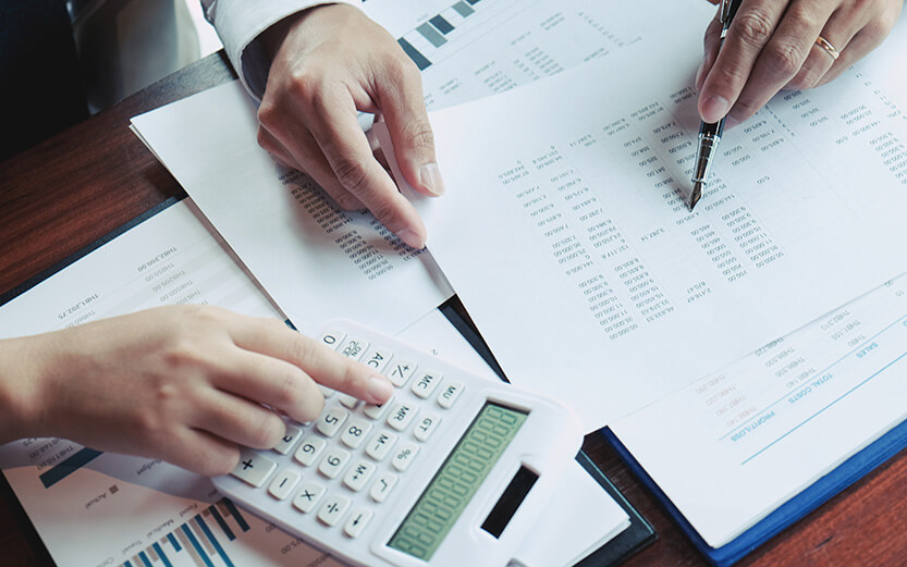 Businessman analyzing investment charts and pressing calculator buttons over documents. Accounting Concept