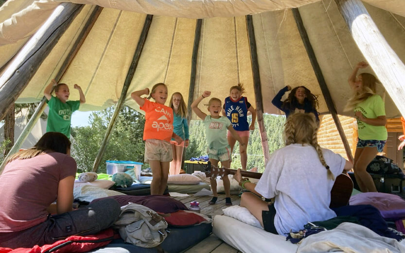 a group of young camper girls dancing and singing in their teepee
