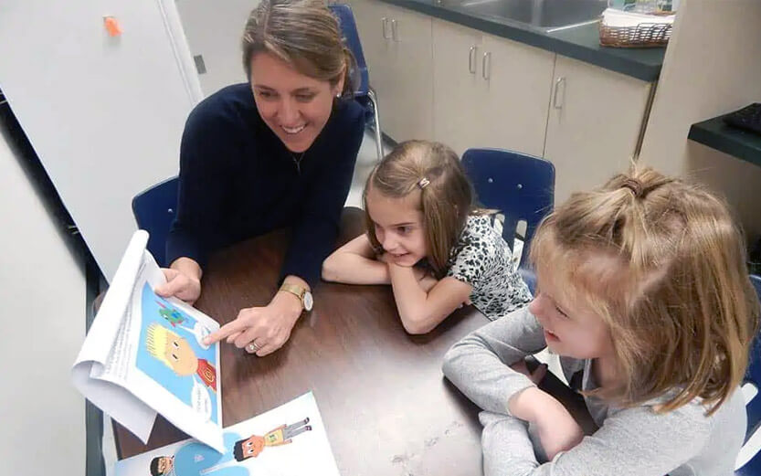 teacher teaching two girls how to read