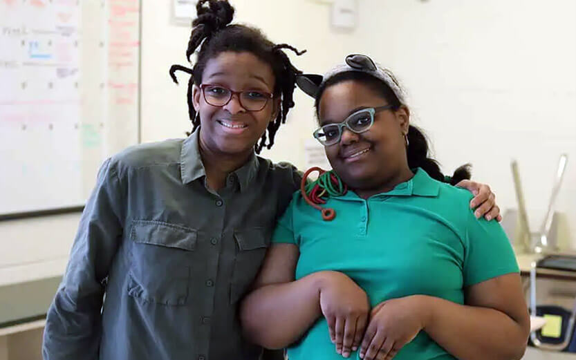 two female students with glasses smiling