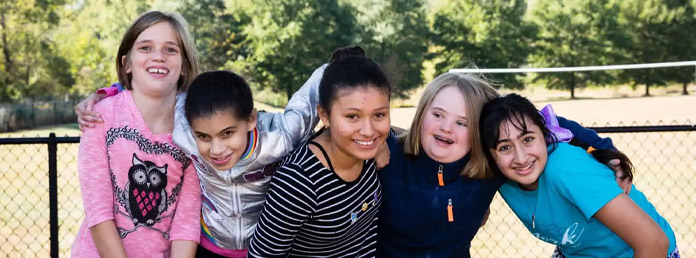 five students with their arms around each other smiling