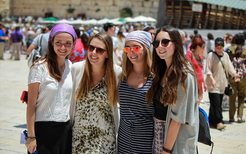 four young adult girls taking a group photo during a trip to Israel