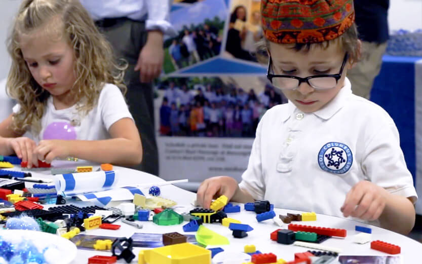 two children at a table playing with Lego blocks