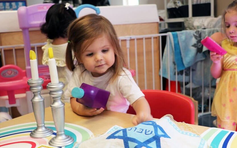 toddler at a play table with various jewish toys