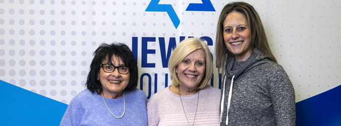 three women at an event standing in front of a banner with the JewishColumbus logo