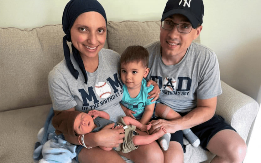 a family of four sitting on a couch with their newborn