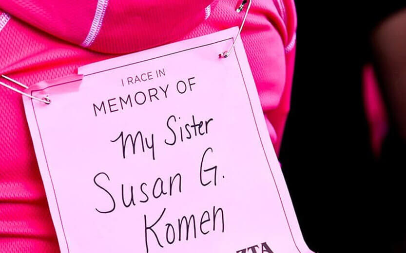 close up shot of an In Memory Of sign pinned to the back of their pink shirt
