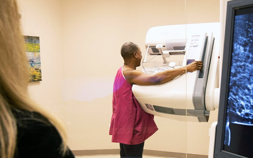 a woman in a pink gown having a mammogram done