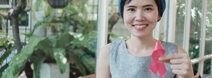 woman holding a pink ribbon and smiling