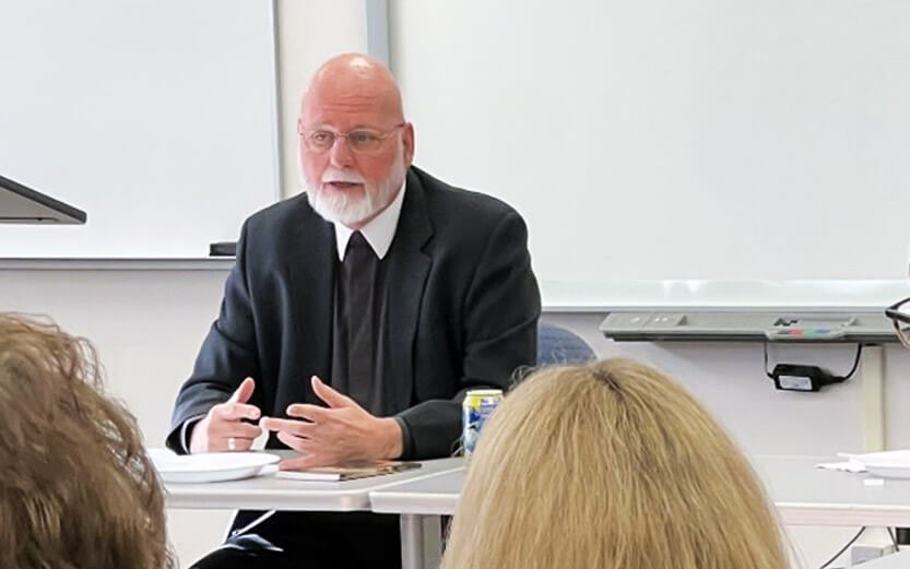 a teacher seated in front of the classroom speaking to students