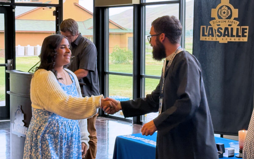 a man shaking the hand of a student at a ceremony