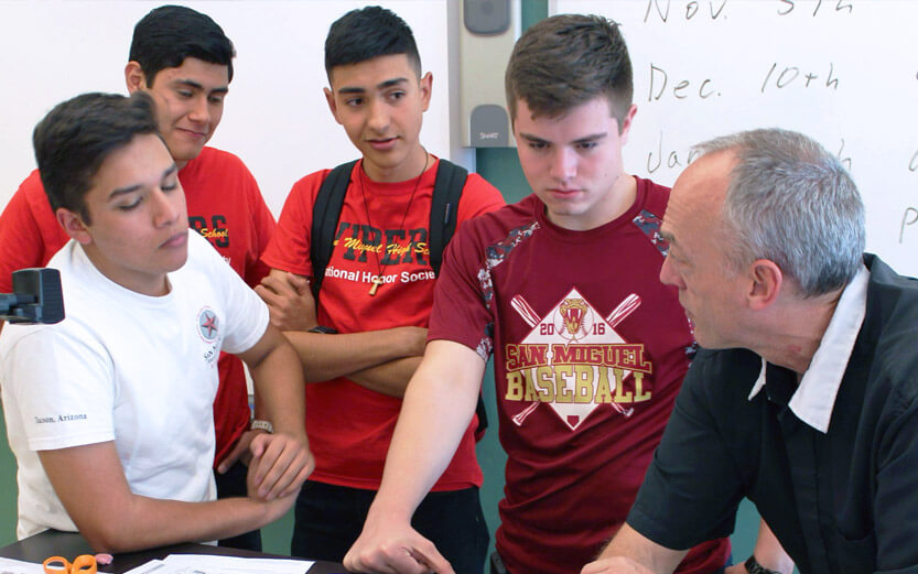 four students speaking with their instructor