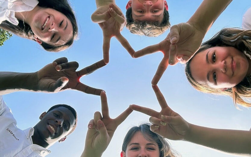 a group of students in a circle forming a star with their fingers
