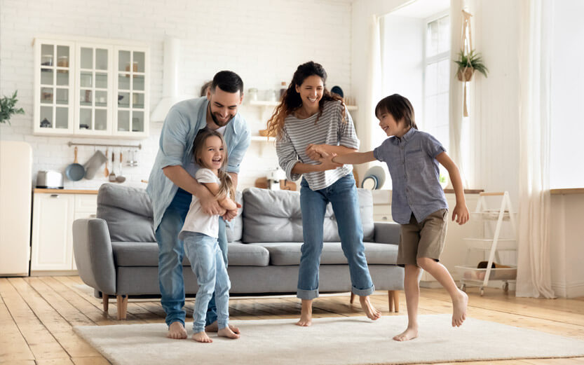 a family of four dancing in their living room
