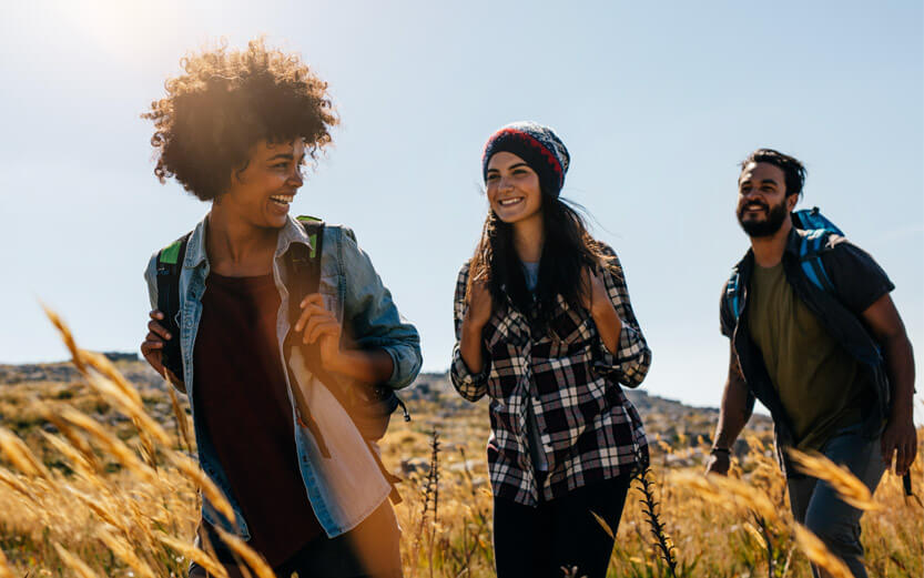three young adults hiking in a field