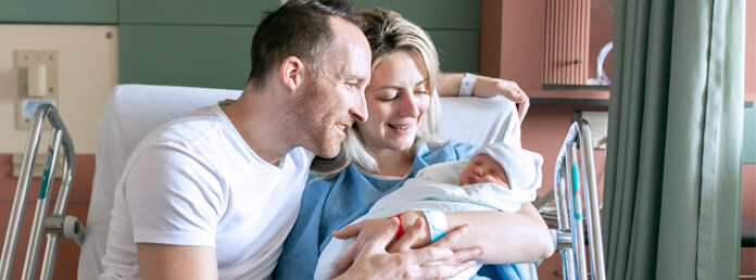 new parents smiling at their newborn in a hospital room