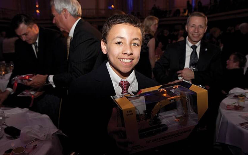 a boy wearing a suit holding a toy tractor
