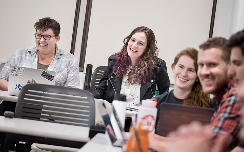 five students in a classroom smiling