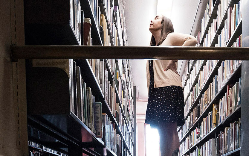 student looking up at books in library