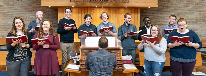 choir practicing holding red songbooks