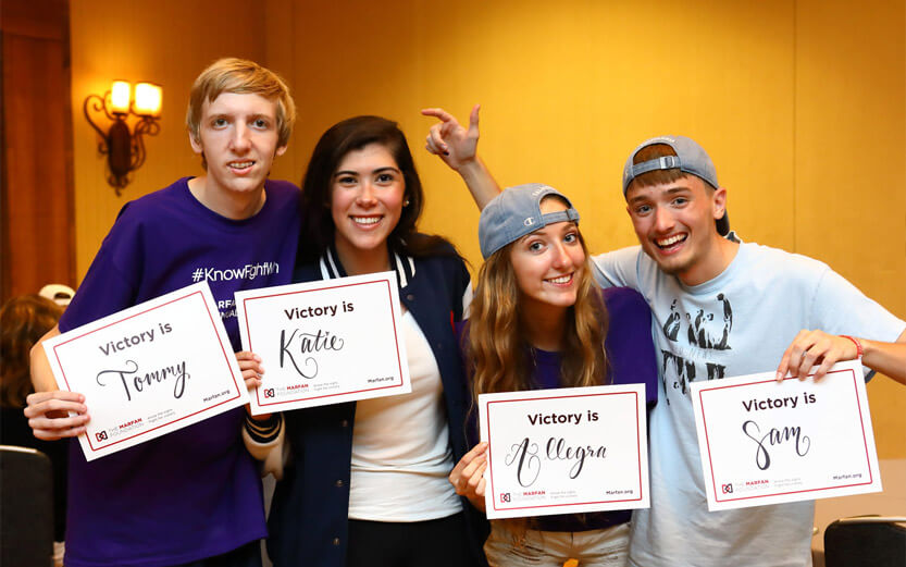 four teens holding signs