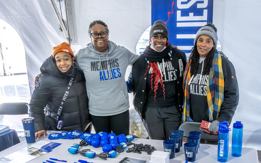 four Memphis Allies workers at an event table smiling