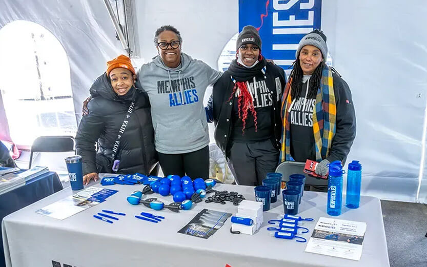 four Memphis Allies workers at an event table smiling